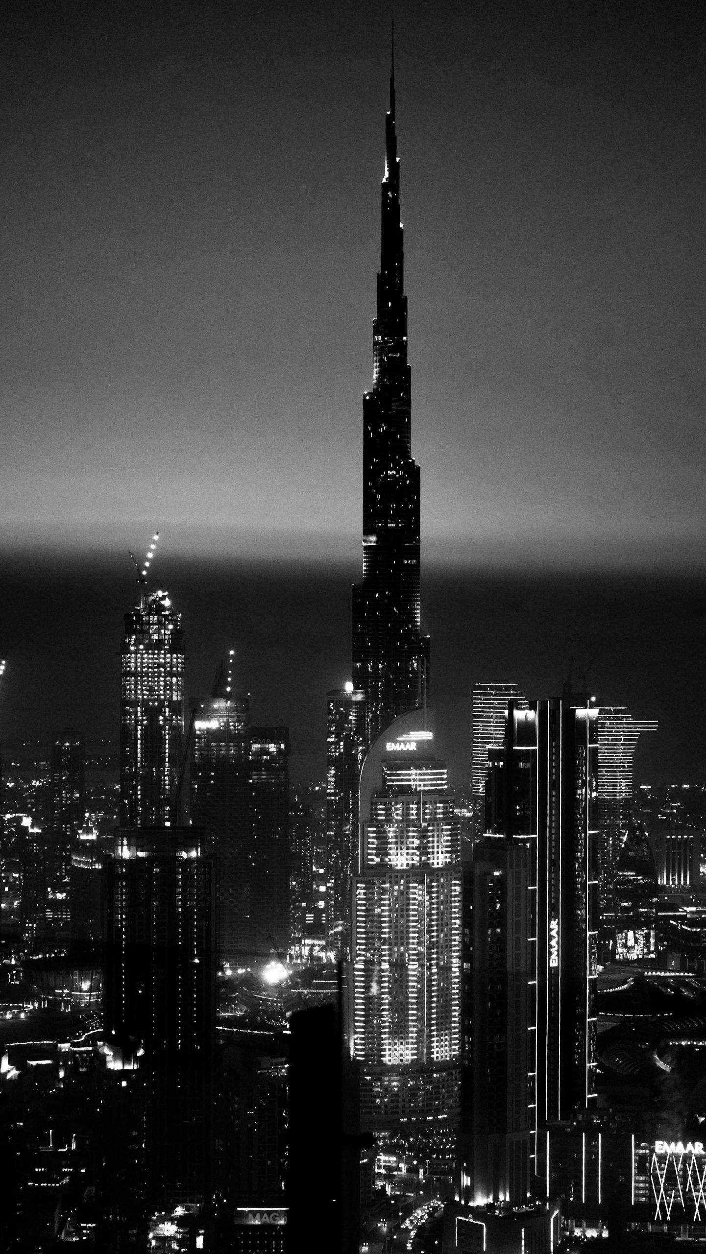Dramatic black and white cityscape of Dubai featuring the iconic Burj Khalifa illuminated at night.
