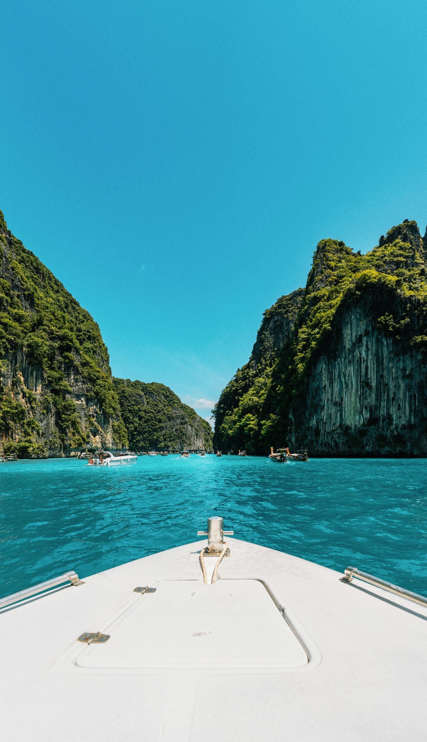 Explore breathtaking turquoise waters and lush limestone cliffs on a boat in Krabi, Thailand.