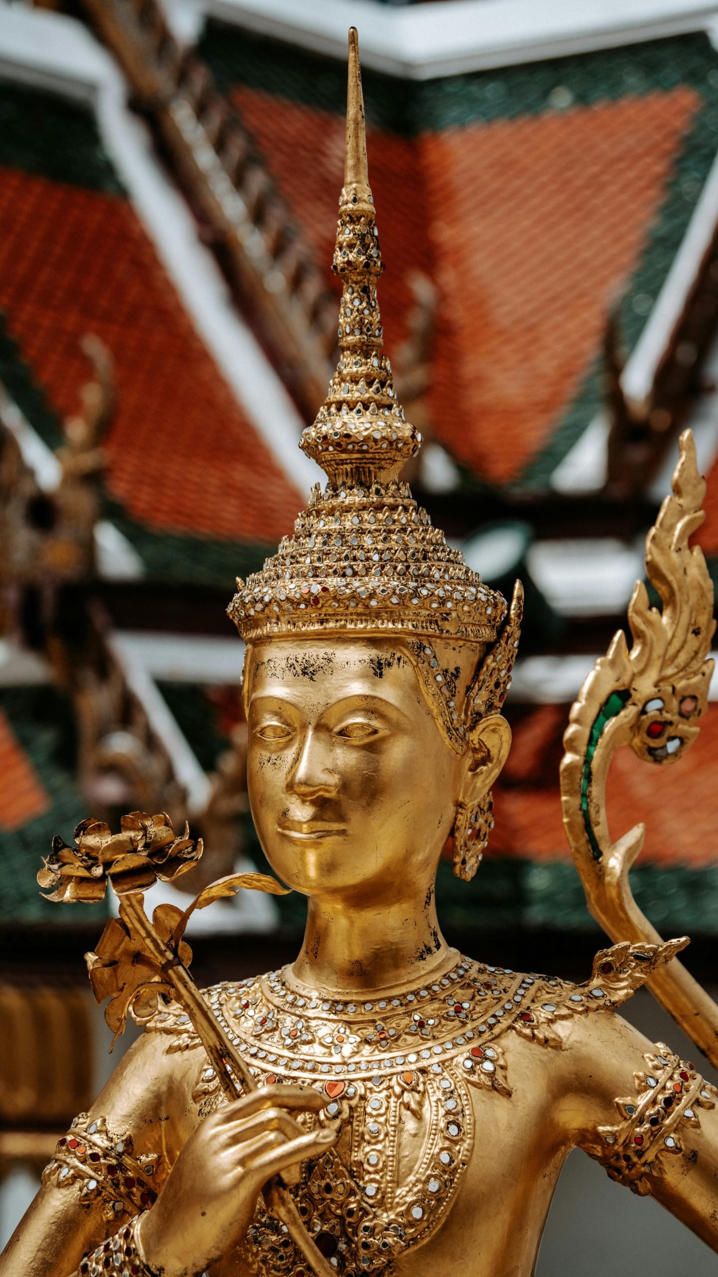 Close-up of an ornate golden statue depicting a mythical figure at Wat Phra Kaew in Bangkok, Thailand.